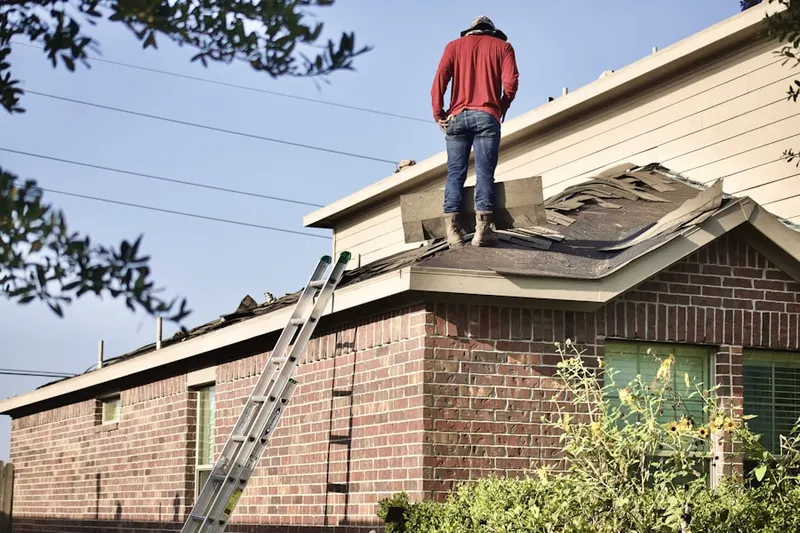 Professional roofer working on a residential roof in Pelham Manor